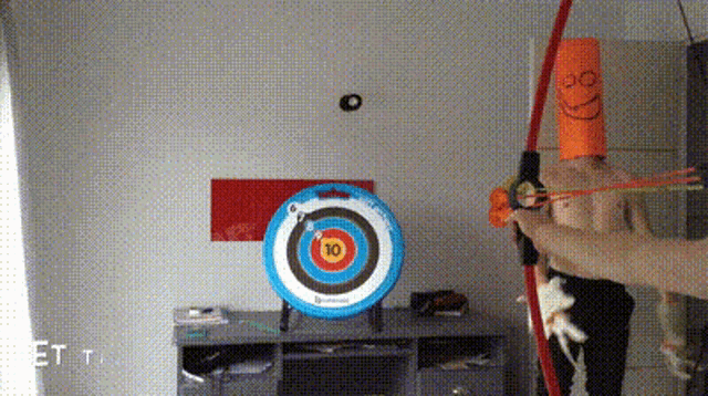 a person is holding a bow and arrow in front of a target that has the number 10 on it
