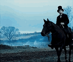 a man in a top hat rides a black horse