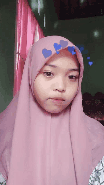 a young girl wearing a pink hijab with blue hearts on it