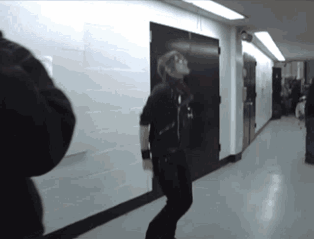 a man in a black jacket is dancing in a hallway next to a door