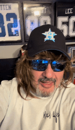 a man wearing sunglasses and a hat with a blue star on it