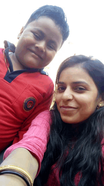 a boy wearing a red shirt with a patch that says ' army ' on it poses for a picture with a woman