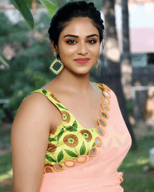 a woman wearing a pink saree and a green blouse with mirrors