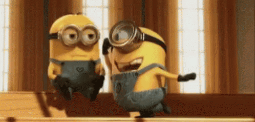 two minions are sitting next to each other on a wooden table .