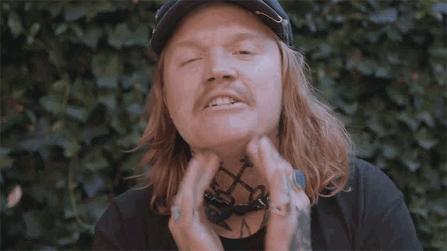 a man with long hair and a bandana around his neck giving a peace sign with his fingers