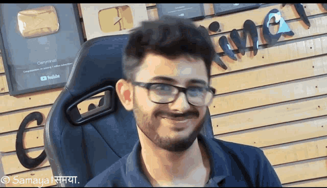 a man with glasses and a beard is smiling in front of a wall that has the word time written on it