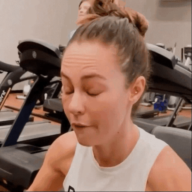 a woman is sitting in front of a treadmill in a gym .