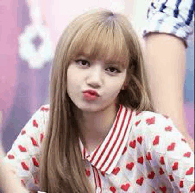 a close up of a woman wearing a shirt with hearts on it and making a funny face .