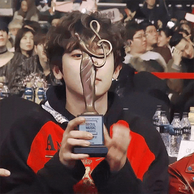 a young man holding a seoul music award