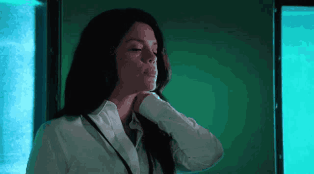 a woman in a white shirt is standing in front of a green wall