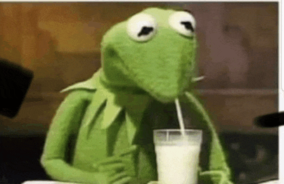 kermit the frog is drinking milk through a straw from a glass .