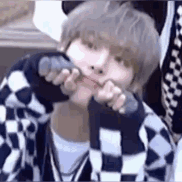 a close up of a person making a funny face with their hands in their mouth .