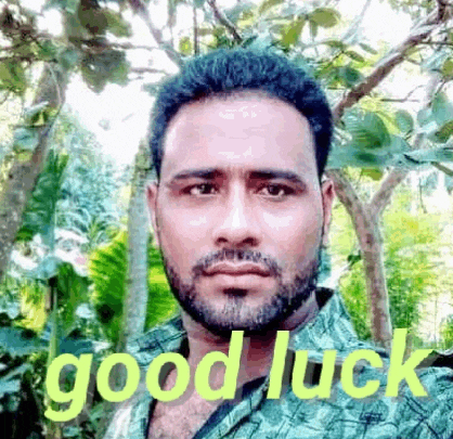 a man with a beard and mustache is standing in front of trees with the words `` good luck '' written on his face .