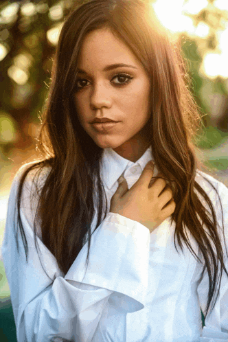 a woman in a white shirt holds her hand to her chest