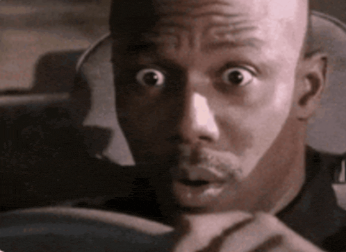 a bald man with a surprised look on his face is driving a car