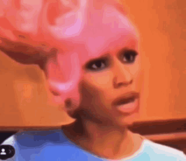 a woman wearing a pink wig is making a funny face .