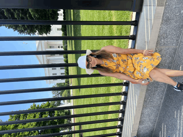 a woman in a yellow dress is standing in front of a white house