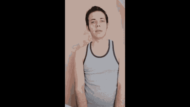 a man in a grey tank top is making a face