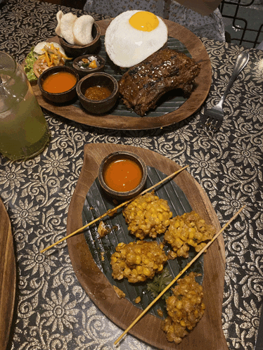 a table topped with plates of food including a steak and eggs