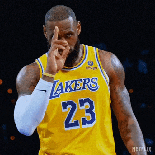 basketball player lebron james is wearing a yellow lakers jersey and pointing at the camera .