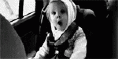 a baby is sitting in a car seat and making a funny face .