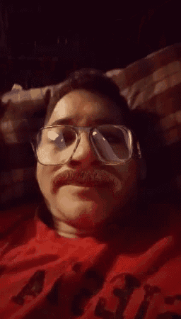 a man wearing glasses is giving a thumbs up sign