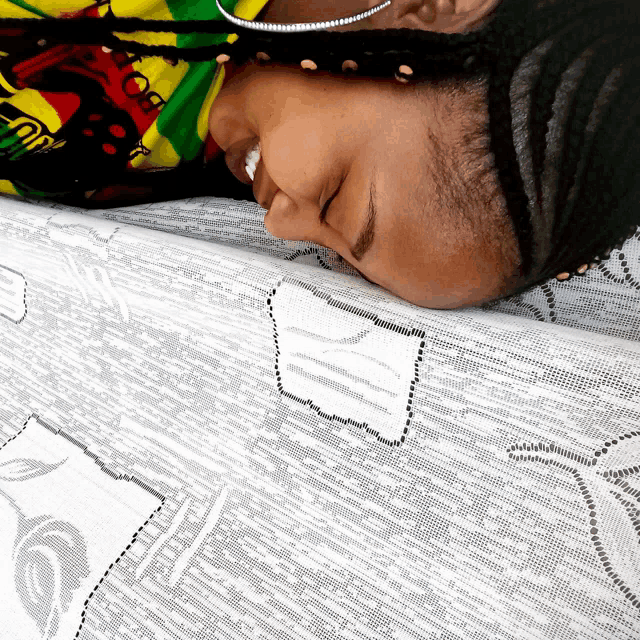 a woman laying on a bed with her eyes closed and a shirt that says ' rasta ' on it