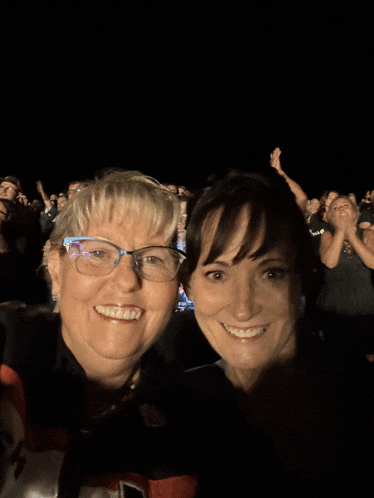 two women are posing for a picture in front of a crowd with one wearing a shirt with the number 14 on it