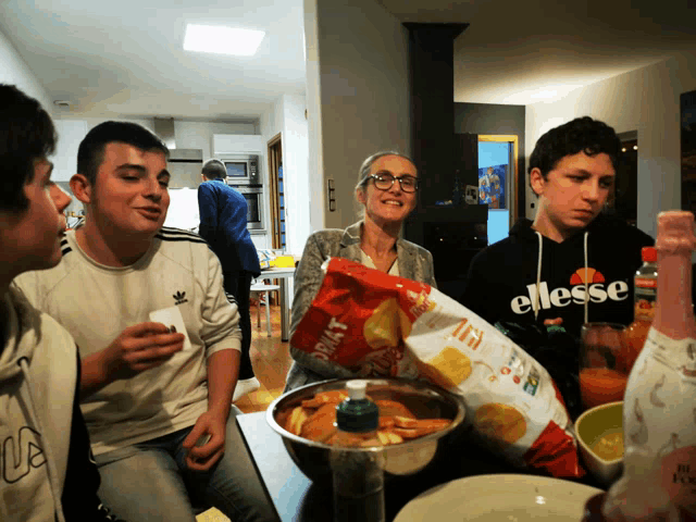 a group of people are sitting around a table with a bag of doritos on it