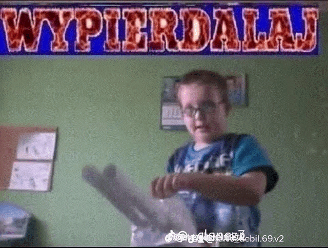 a boy holding a piece of paper in front of a sign that reads wypierdalaj