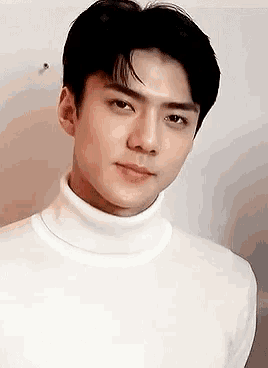 a close up of a man wearing a white turtleneck sweater .