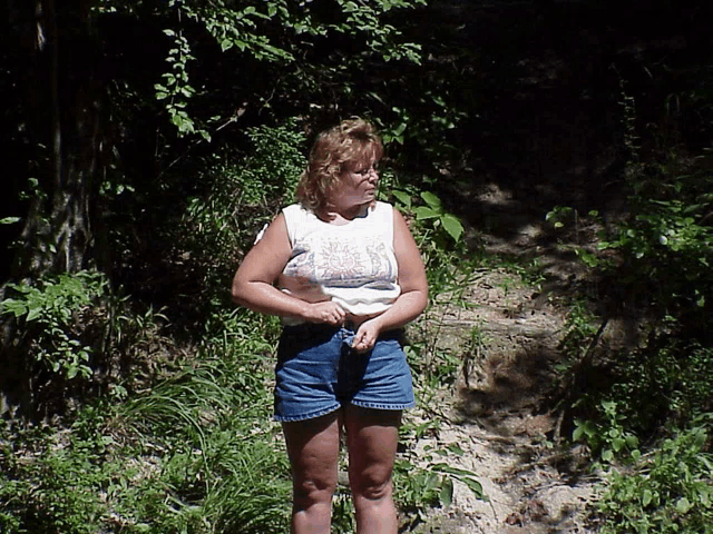 a woman wearing shorts and a white tank top with a floral design on it