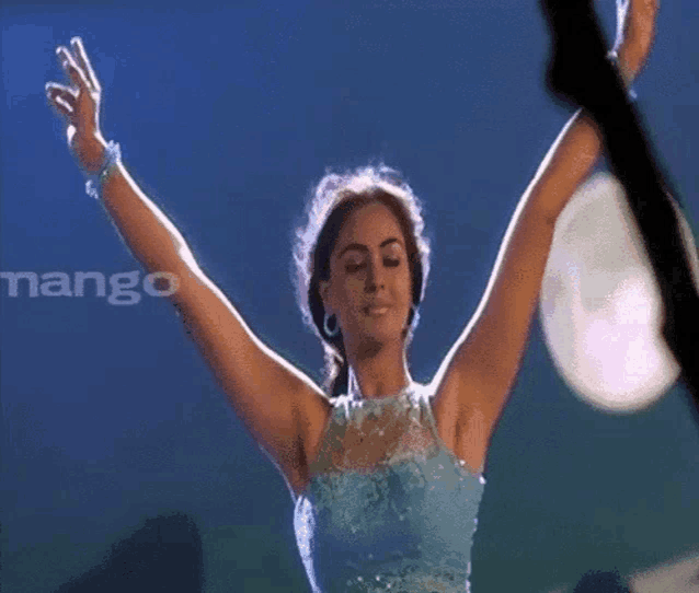 a woman in a blue dress with her arms in the air