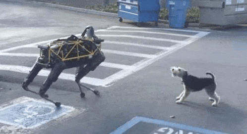 a robot dog is playing with a small dog in a parking lot .