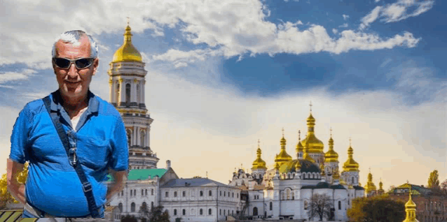 a man wearing sunglasses stands in front of a very large building