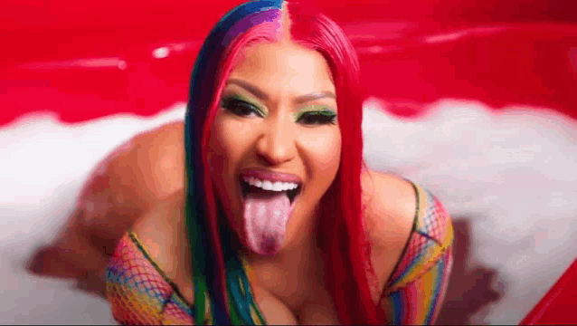 a woman with red hair and rainbow makeup is sticking her tongue out .