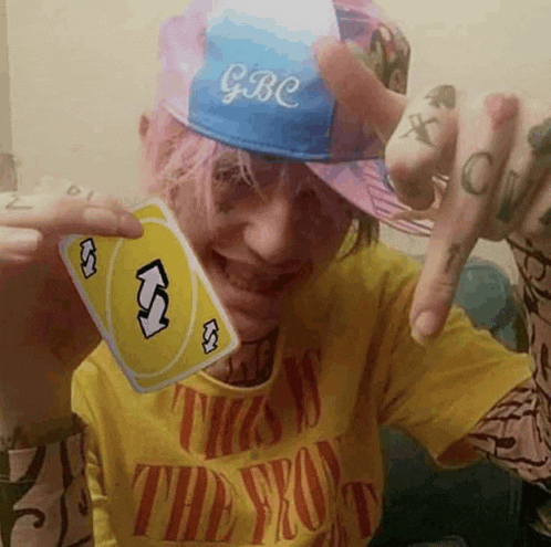 a person wearing a yellow shirt and a blue hat is holding a uno card .