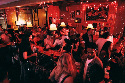 a crowd of people are gathered at a bar with a sign on the wall that says ' a ' on it