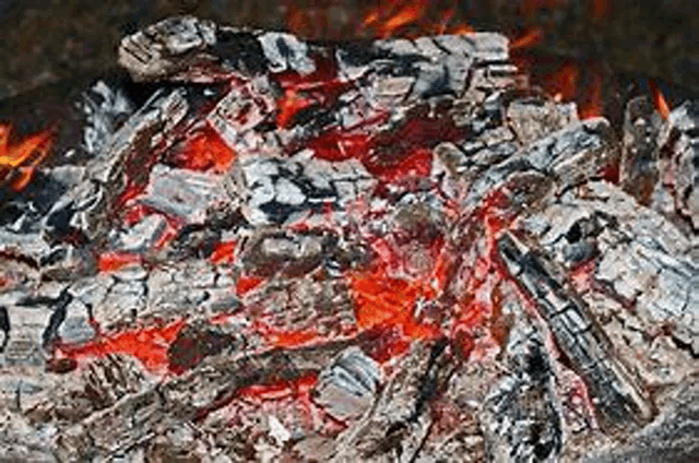 a close up of a pile of burning coals with flames coming out of them .