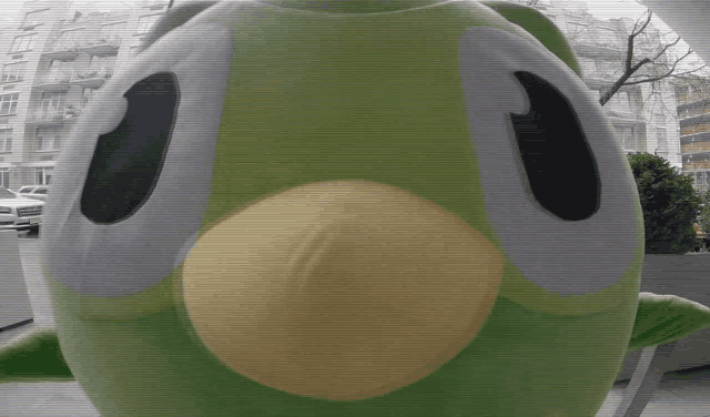 a green frog mascot with a yellow beak and large eyes