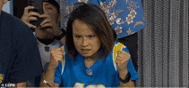 a woman in a blue shirt is sitting in a stadium holding her fist up .