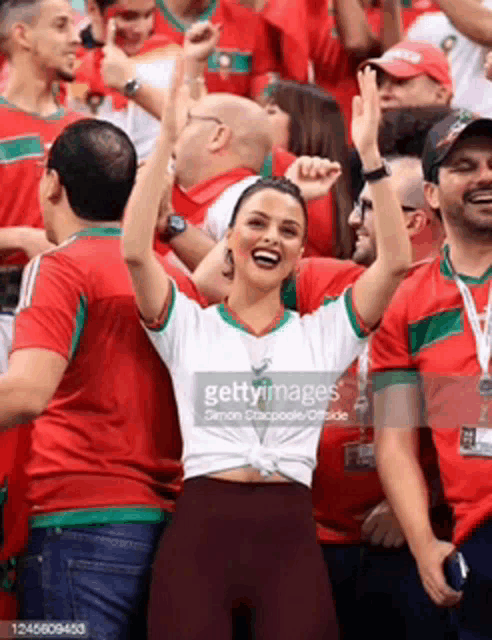 a woman in a white shirt is standing in a crowd of people .