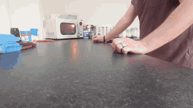 a man in a brown shirt is standing in a kitchen with a bag of peanut butter in the background