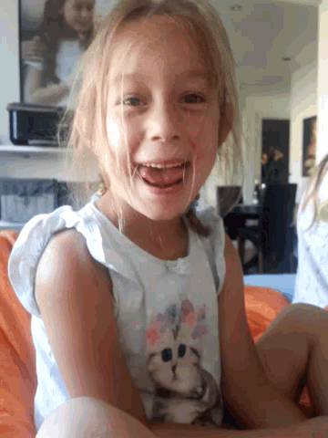 a little girl with a cat on her shirt smiles for the camera
