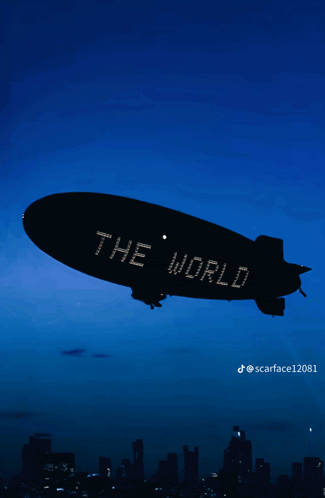 a blimp that says the world is flying in the night sky