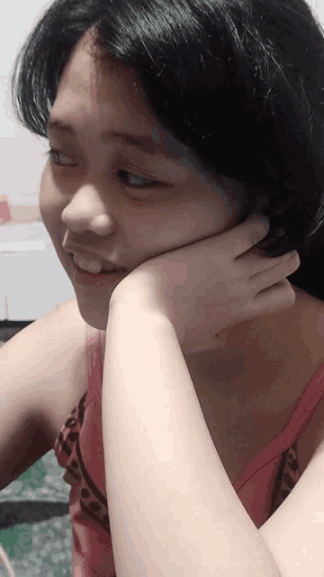 a woman in a pink tank top with her hand on her chin