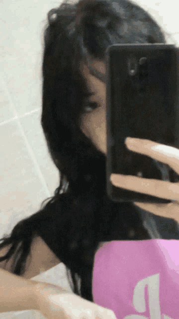 a woman is taking a selfie with her phone and a pink bag with the letter l on it