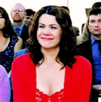 a woman in a red sweater is smiling in a crowd of people