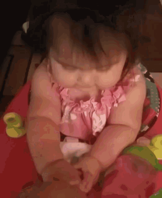 a baby in a pink dress is sitting in a red bouncer