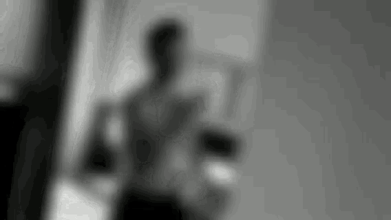 a blurry black and white photo of a man taking a selfie in a bathroom .